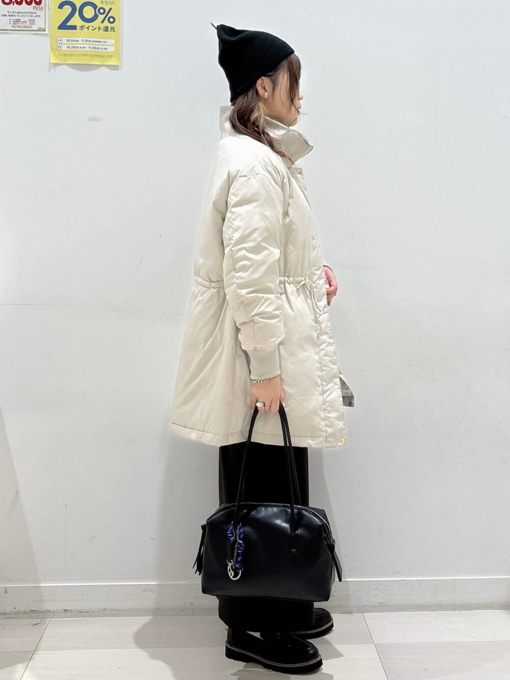 ベージュ系のダウンジャケット/コート、ブラック系のボストンバッグ、ブラック系のローファーを着用したレディースの秋コーディネートの2枚目の写真