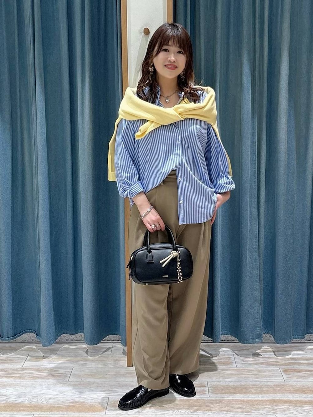 ブラック系のローファー、ブラック系のハンドバッグ、イエロー系のニット/セーターを着用したレディースの春コーディネートの4枚目の写真