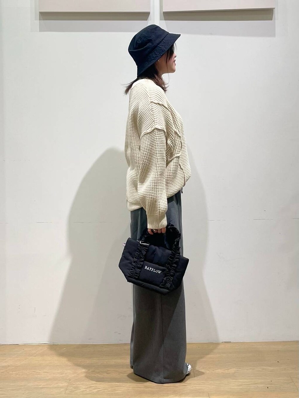 グレー系のその他パンツ、ブラック系のトートバッグ、ホワイト系のニット/セーターを着用したレディースの秋コーディネートの2枚目の写真