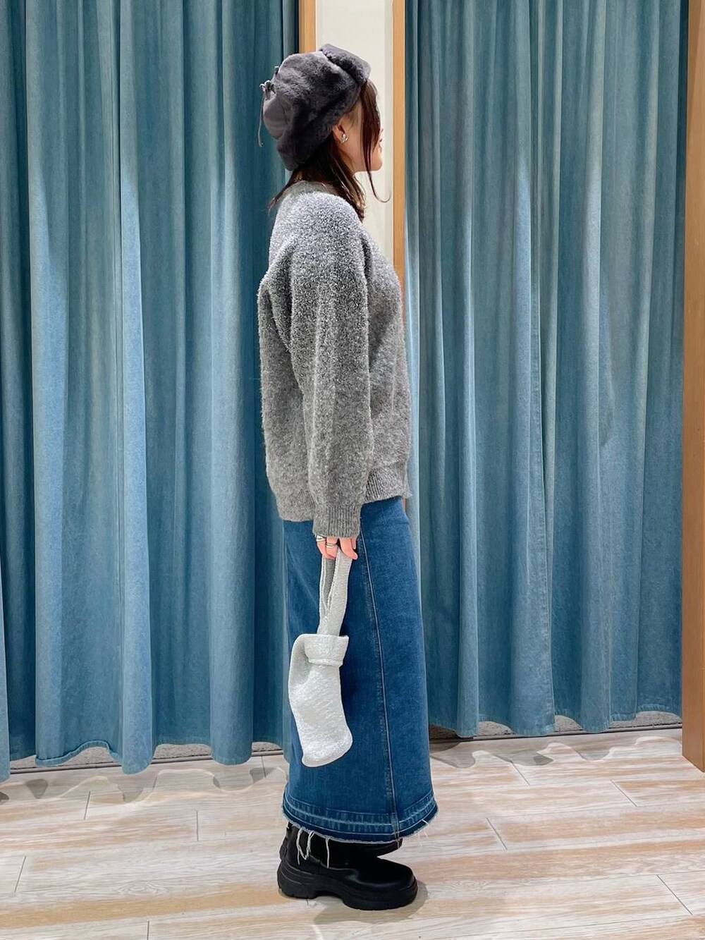 ブルー系のデニムスカート、ブラック系のブーツ、グレー系のハンドバッグを着用したレディースの冬コーディネートの2枚目の写真