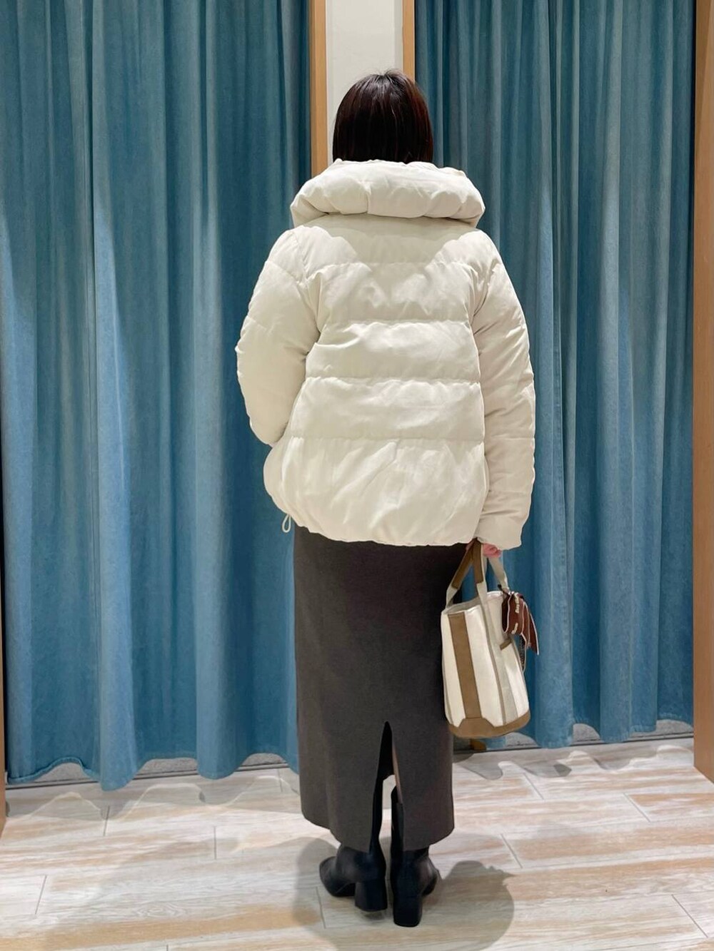 ホワイト系のダウンジャケット/コート、ブラック系のブーツ、ホワイト系のトートバッグを着用したレディースの冬コーディネートの2枚目の写真