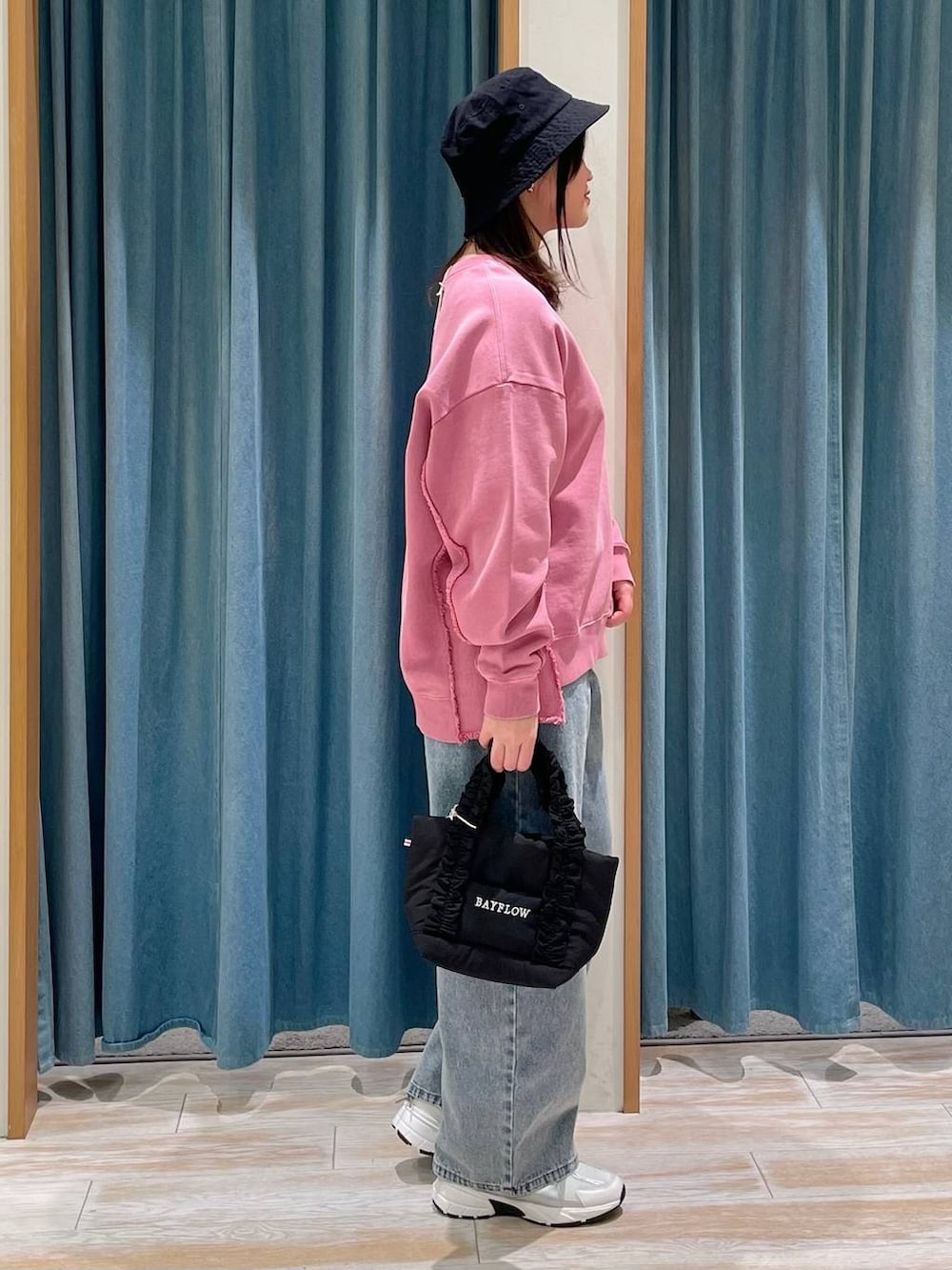 ブラック系のトートバッグ、ブルー系のデニムパンツ、ホワイト系のスニーカーを着用したレディースの冬コーディネートの2枚目の写真