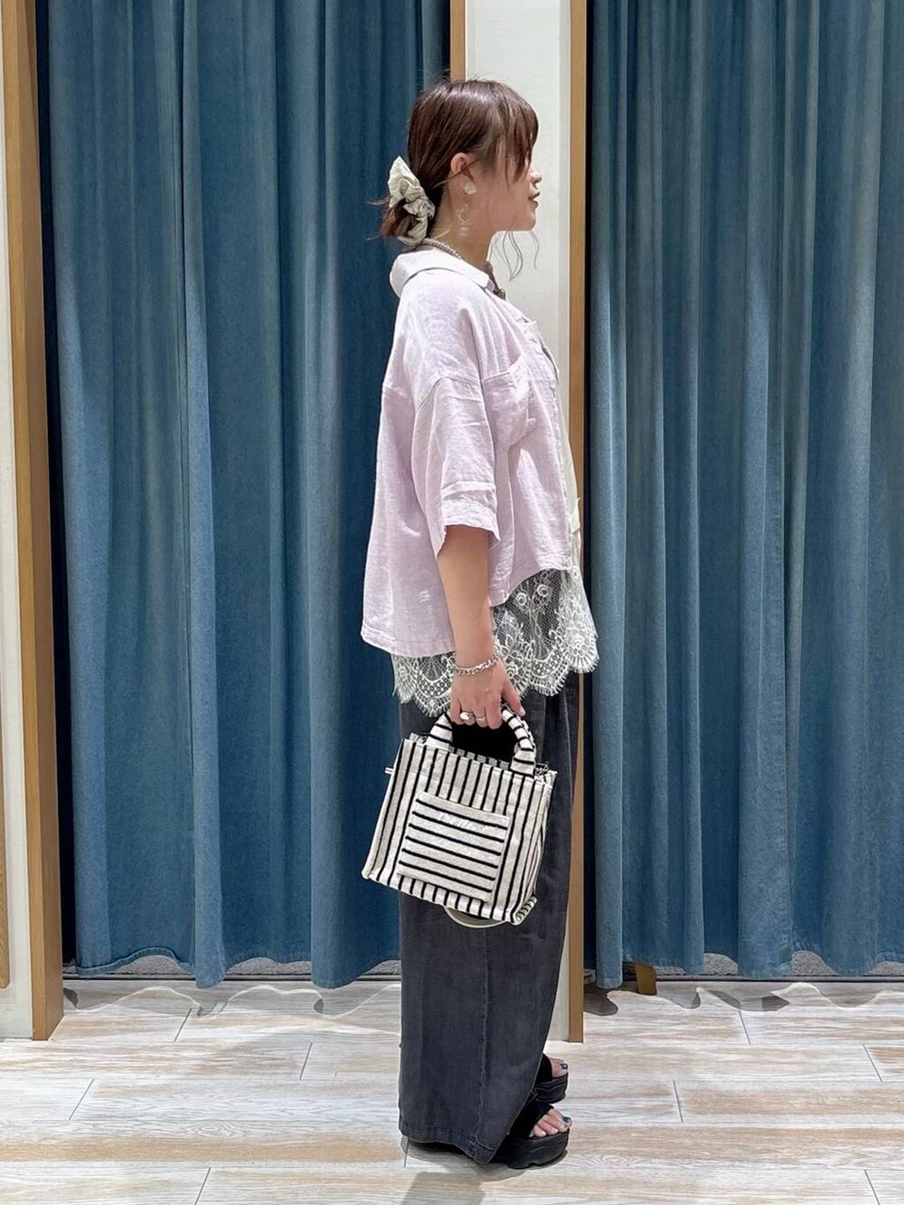 ブラック系のデニムパンツ、ベージュ系のトートバッグ、パープル系のシャツ/ブラウスを着用したレディースの春コーディネートの2枚目の写真