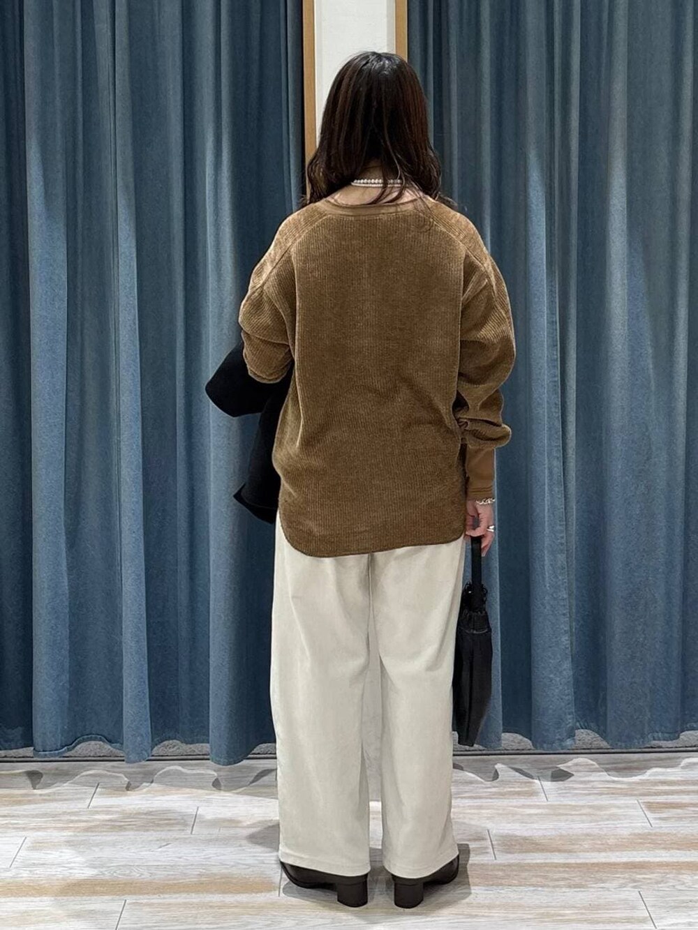 ブラック系のブルゾン、ブラウン系のブーツ、ブラック系のハンドバッグを着用したレディースの秋コーディネートの3枚目の写真