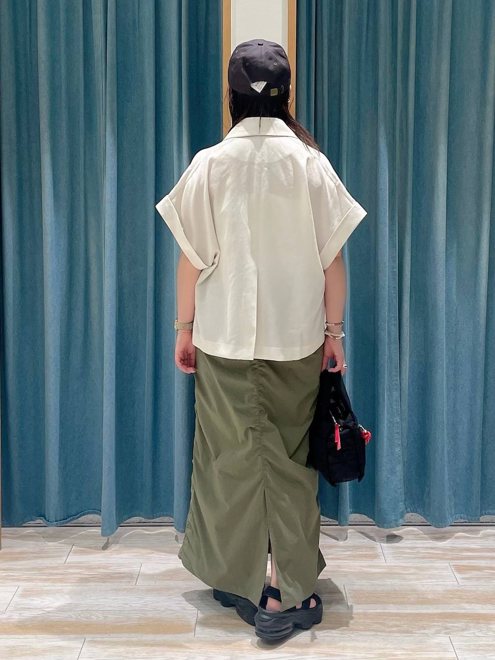 ホワイト系のキャミソール、ブラック系のショルダーバッグ、グリーン系のスカートを着用したレディースの夏コーディネートの3枚目の写真