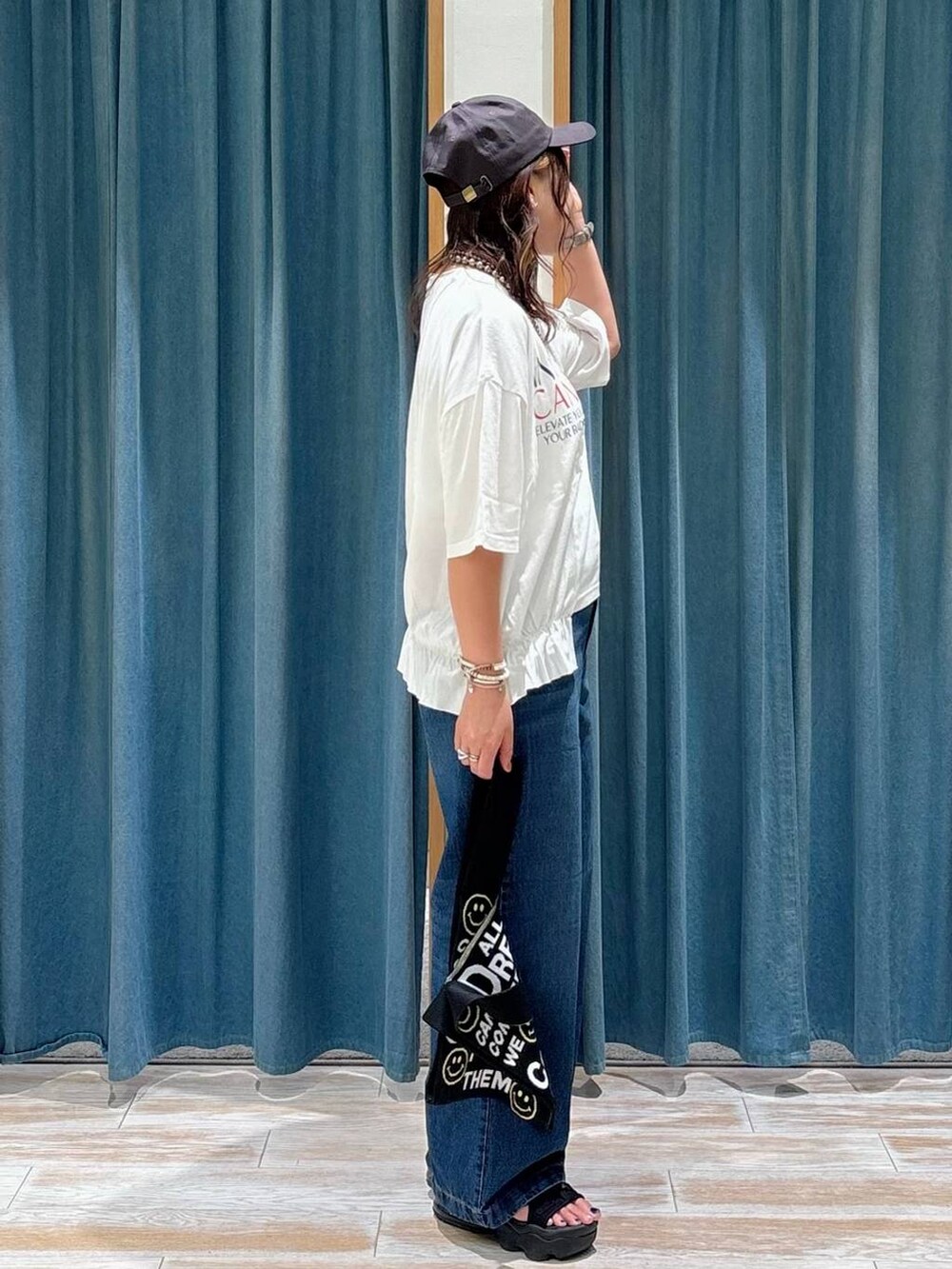 ブルー系のデニムパンツ、ブラック系のトートバッグ、シルバー系のネックレスを着用したレディースの夏コーディネートの2枚目の写真