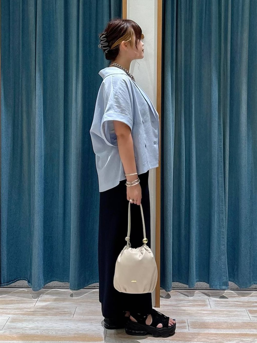 ホワイト系のキャミソール、ホワイト系のショルダーバッグ、ブラック系のスカートを着用したレディースの夏コーディネートの2枚目の写真