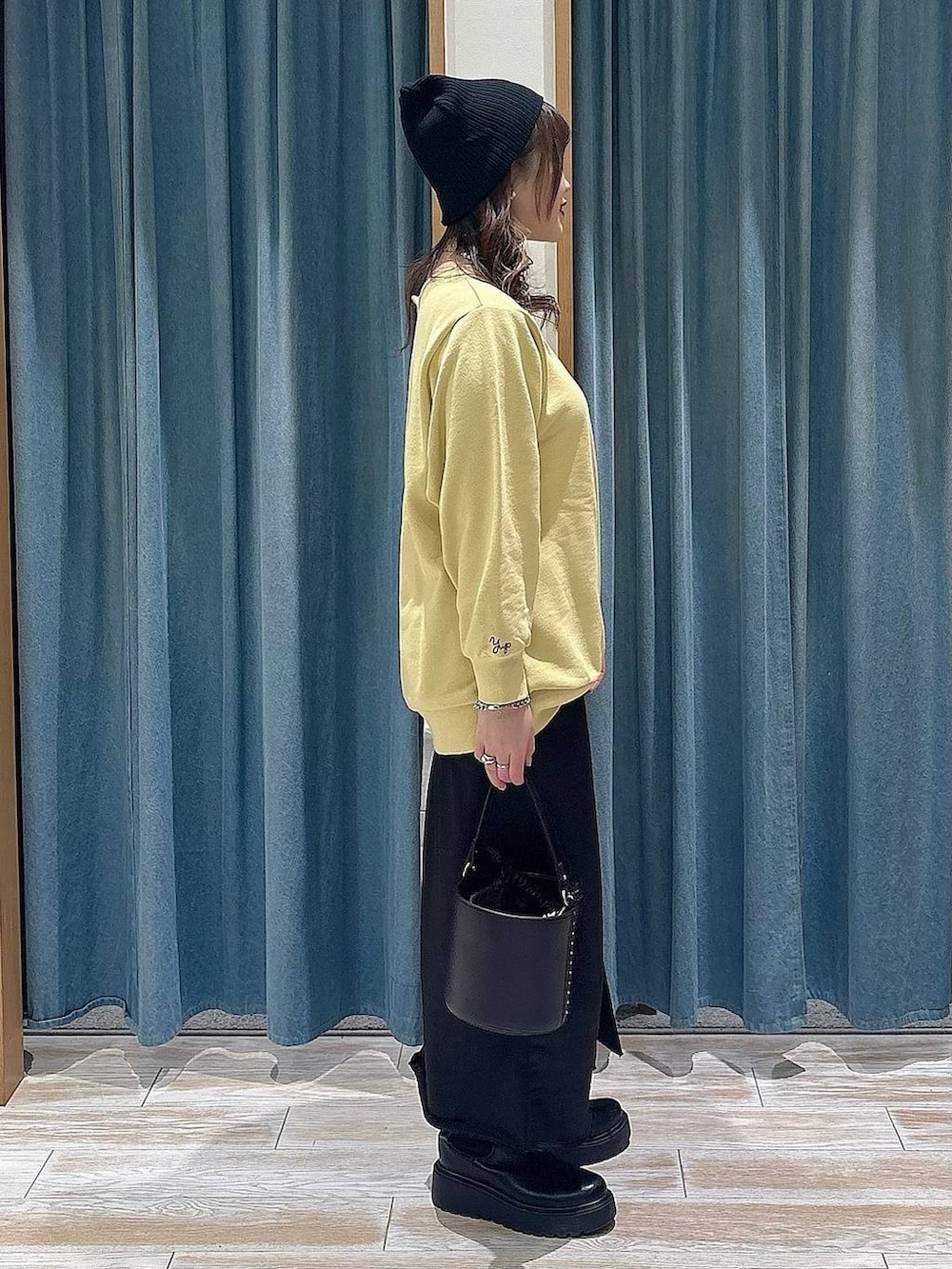 ブラック系のブーツ、イエロー系のスウェット、ブラック系のスカートを着用したレディースの冬コーディネートの2枚目の写真