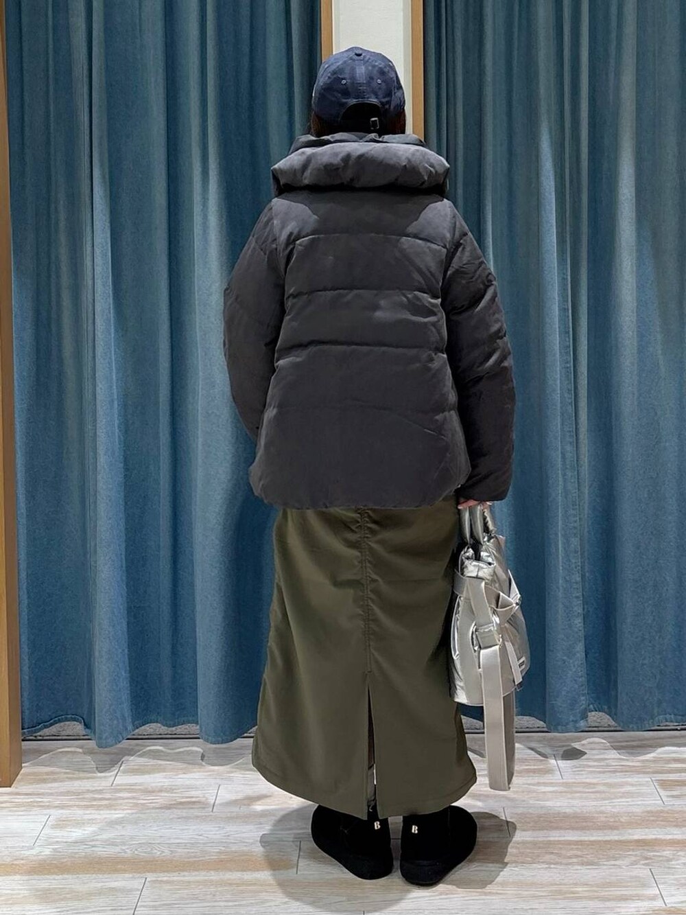 シルバー系のトートバッグ、グリーン系のスカート、グレー系のダウンジャケット/コートを着用したレディースの秋コーディネートの3枚目の写真