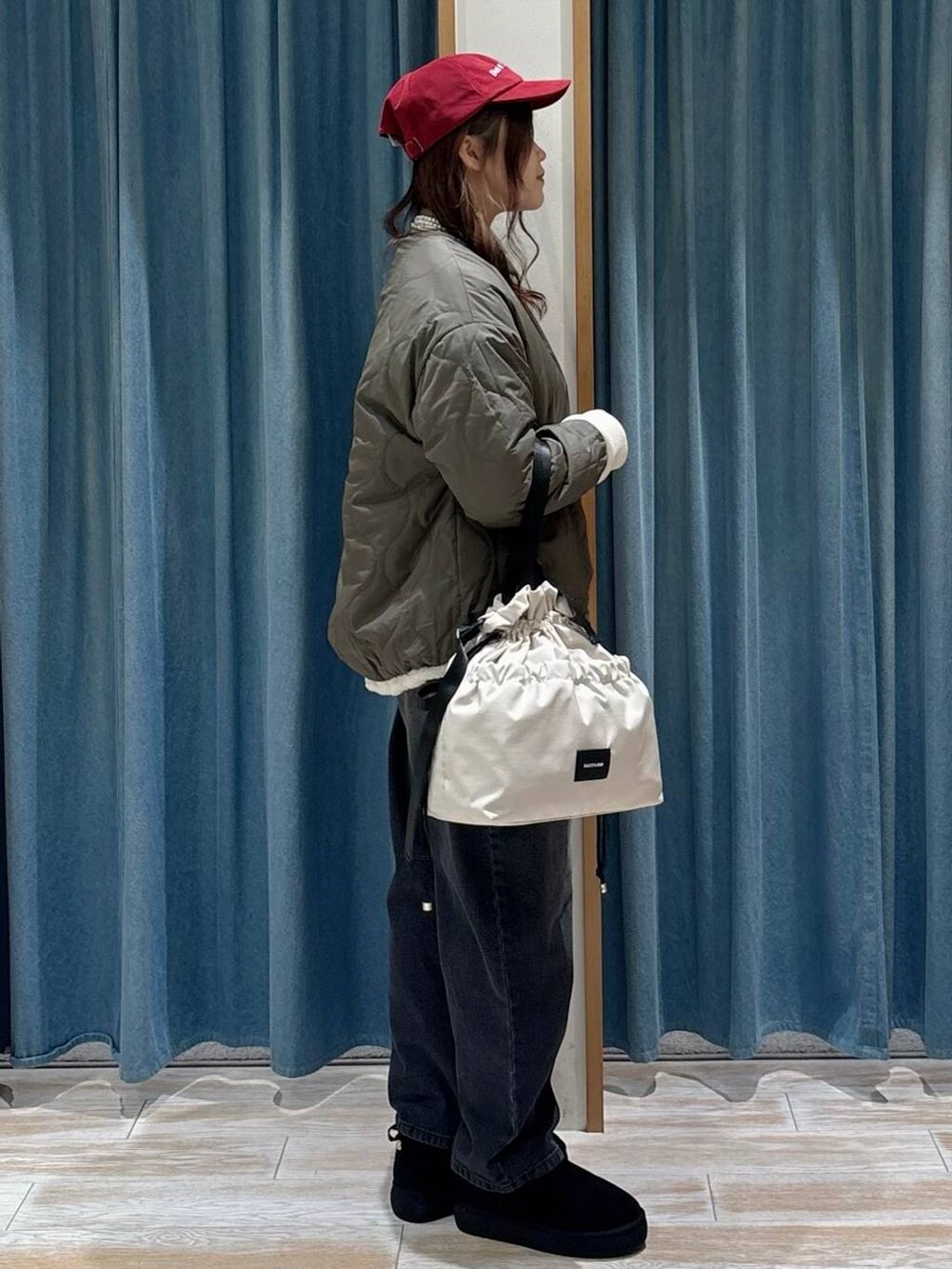 ホワイト系のトートバッグ、ブラック系のブーツ、ホワイト系のブルゾンを着用したレディースの秋コーディネートの2枚目の写真