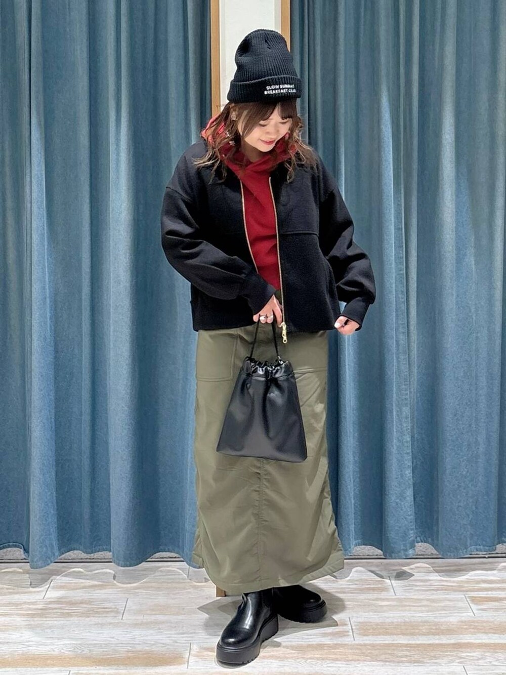 グリーン系のスカート、ブラック系のブルゾン、ブラック系のブーツを着用したレディースの秋コーディネートの4枚目の写真