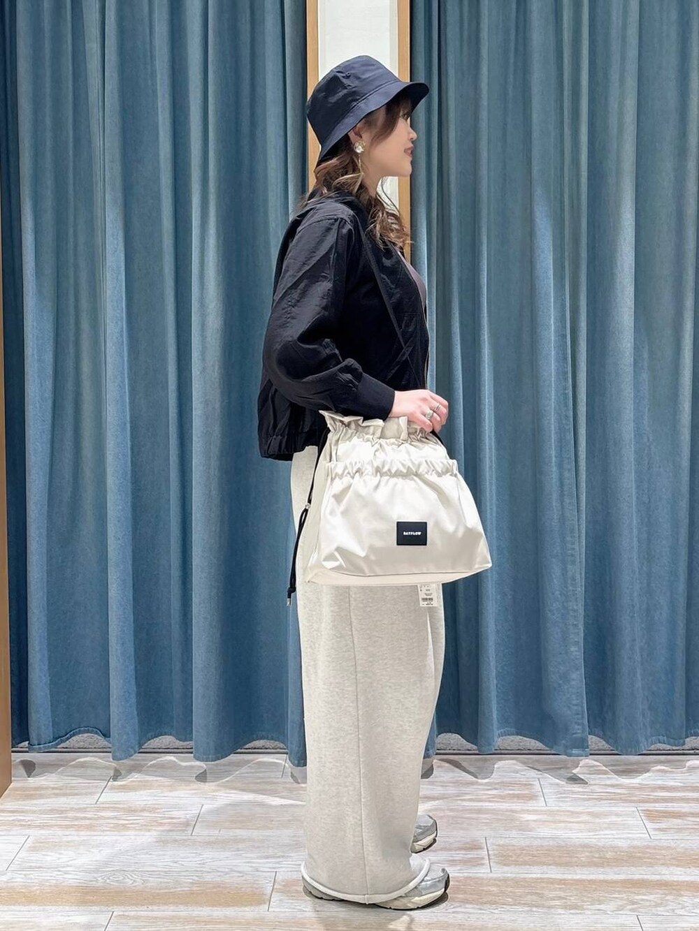 ホワイト系のトートバッグ、ブラック系のブルゾン、ホワイト系のスウェットパンツを着用したレディースの春コーディネートの2枚目の写真