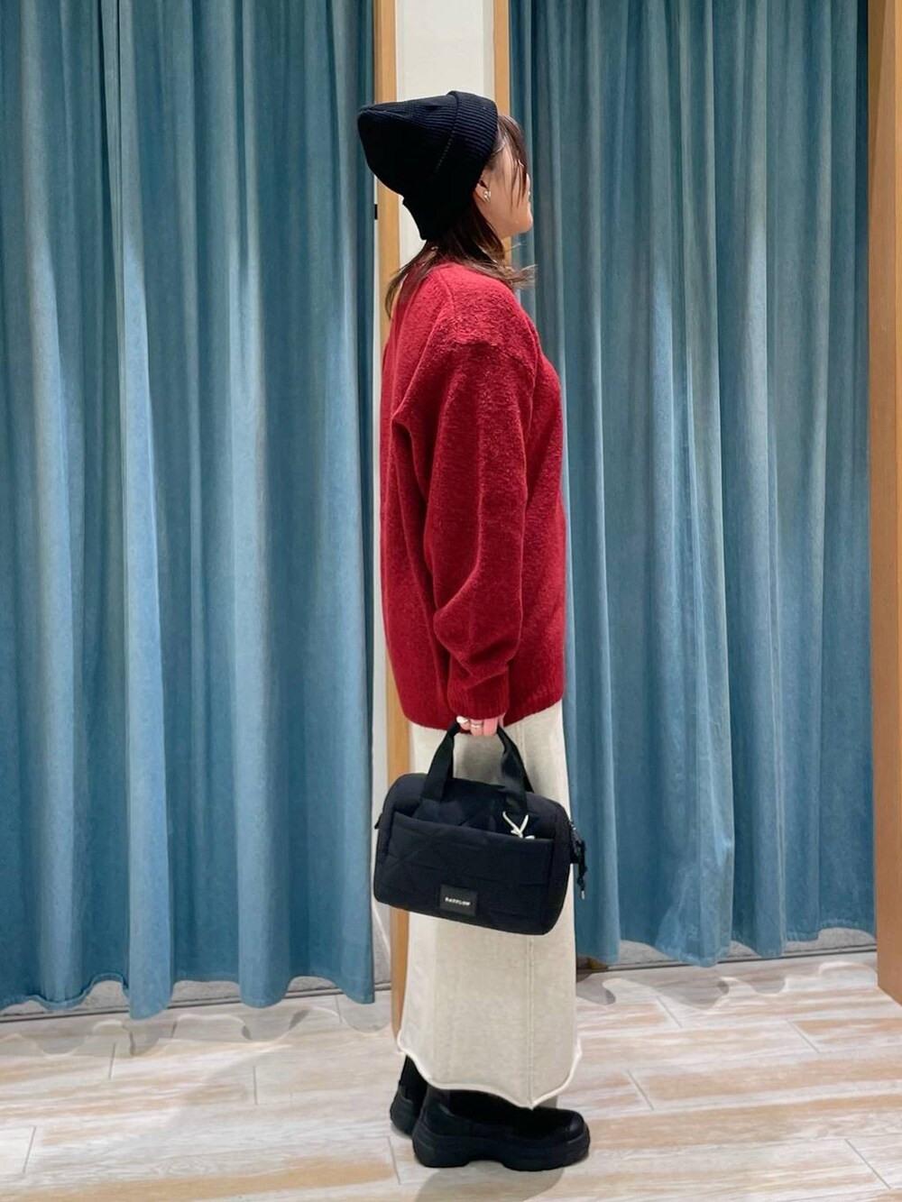 ブラック系のブーツ、ブラック系のハンドバッグ、レッド系のニット/セーターを着用したレディースの冬コーディネートの2枚目の写真