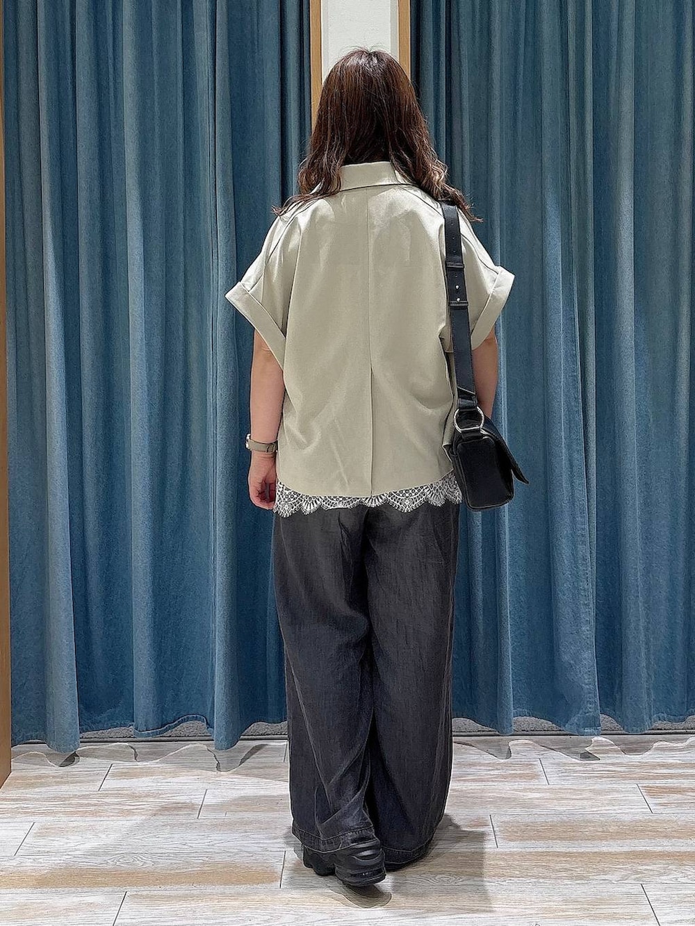 ブラック系のデニムパンツ、ブラック系のショルダーバッグ、ホワイト系のキャミソールを着用したレディースの夏コーディネートの3枚目の写真