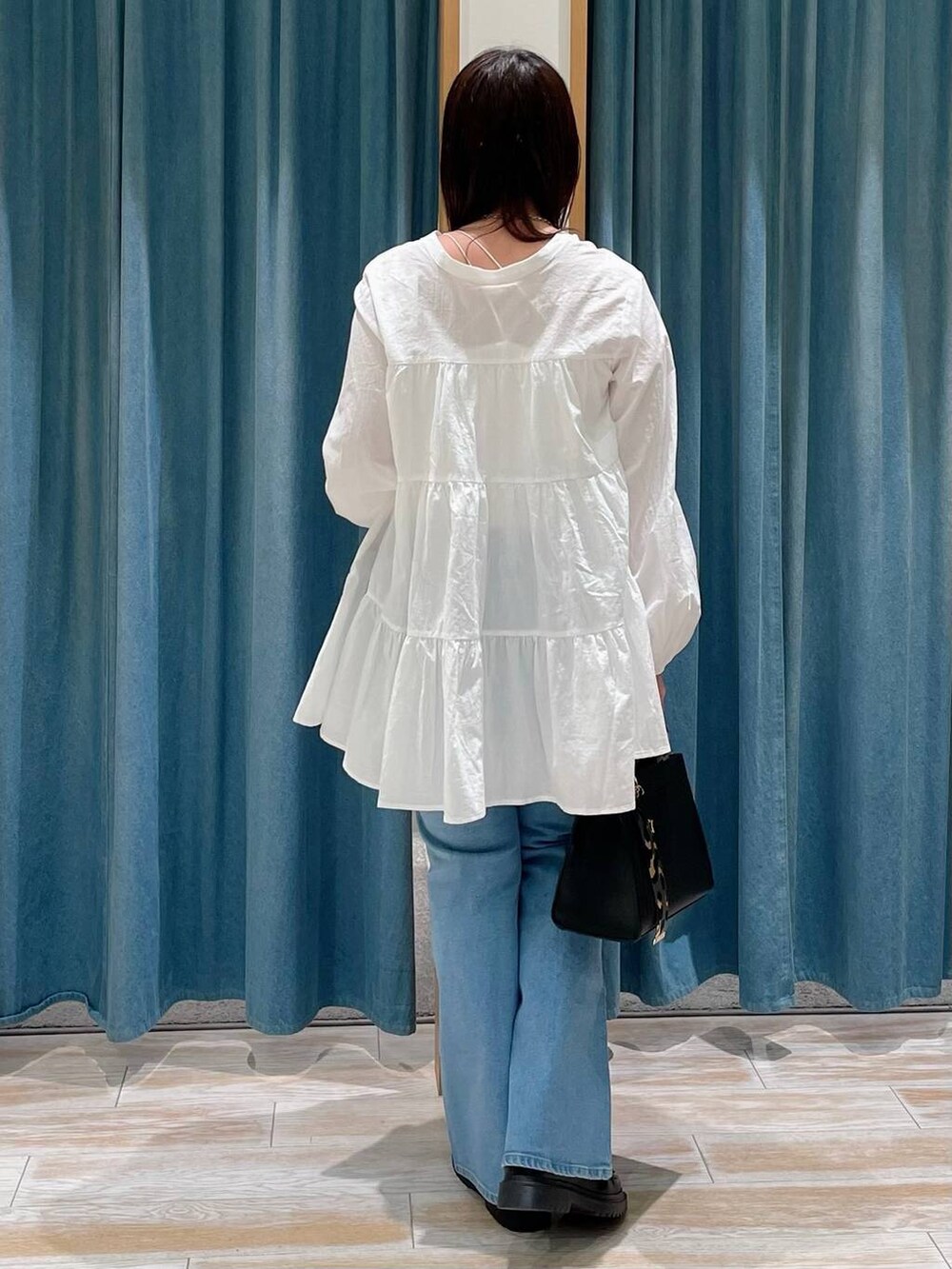 ブラック系のハンドバッグ、その他のローファー、ブルー系のデニムパンツを着用したレディースの冬コーディネートの3枚目の写真