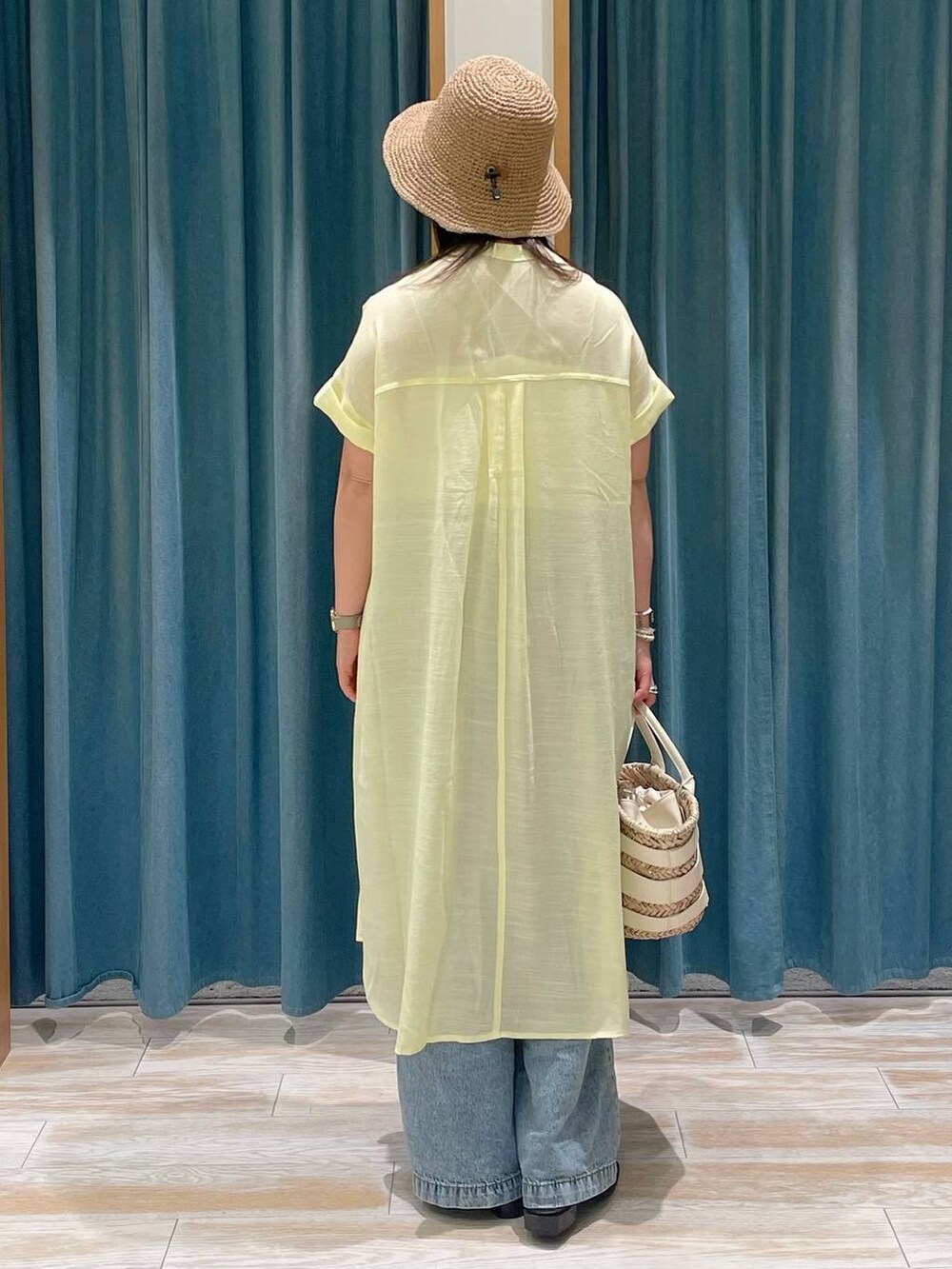 ホワイト系のキャミソール、ホワイト系のかごバッグ、ブルー系のデニムパンツを着用したレディースの春コーディネートの3枚目の写真