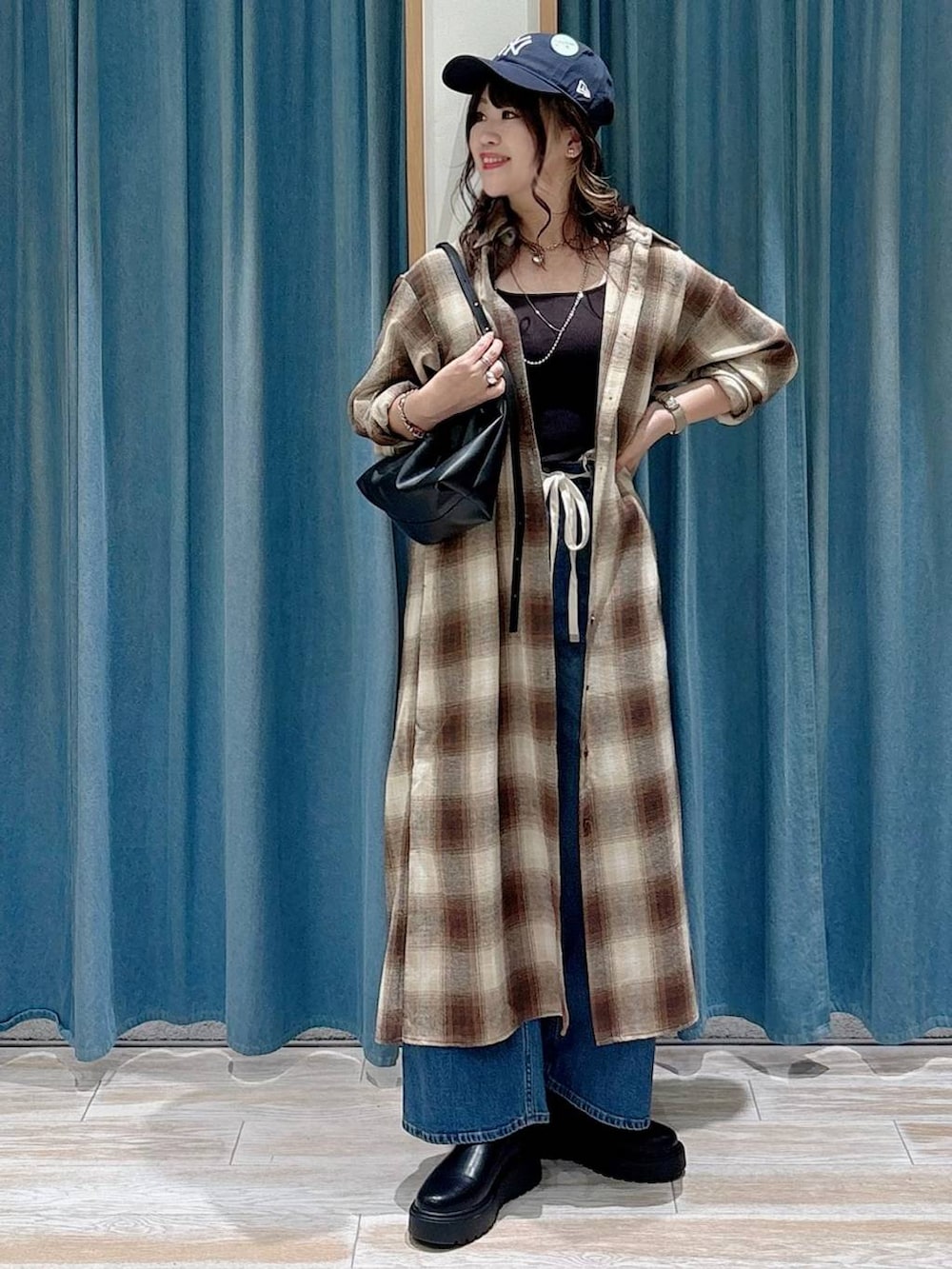 ブラック系のキャミソール、ブラック系のブーツ、ブラック系のハンドバッグを着用したレディースの秋コーディネートの4枚目の写真