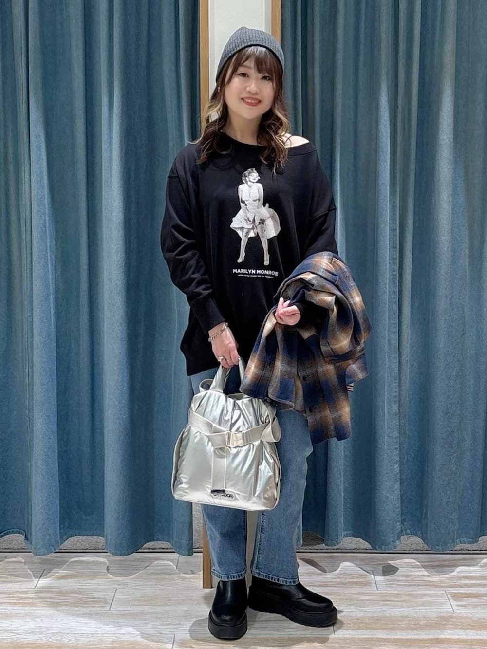 シルバー系のトートバッグ、ブルー系のデニムパンツ、ブラック系のスウェットを着用したレディースの冬コーディネートの4枚目の写真