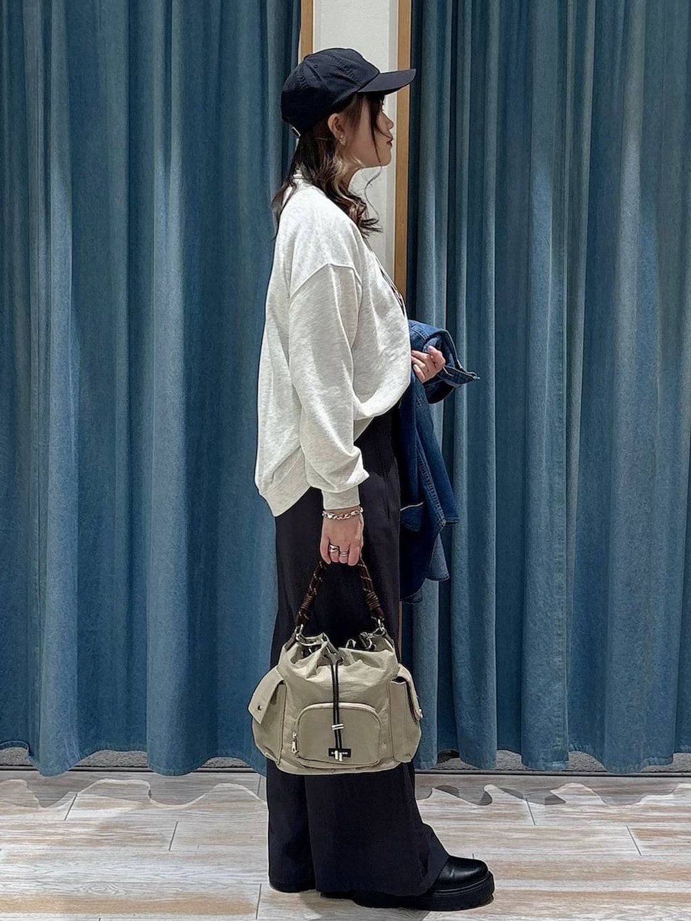 ブラック系のブーツ、ベージュ系のハンドバッグ、ホワイト系のスウェットを着用したレディースの冬コーディネートの2枚目の写真