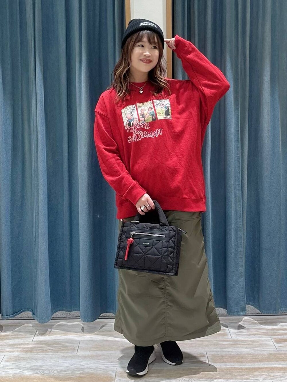 ブラック系のショルダーバッグ、グリーン系のスカート、ブラック系のブーツを着用したレディースの冬コーディネートの4枚目の写真