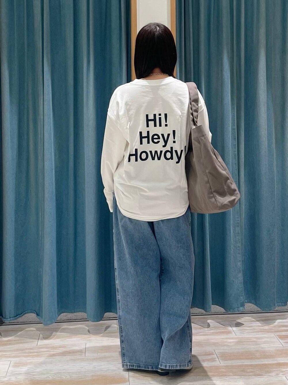 ブルー系のデニムパンツ、ホワイト系のTシャツ/カットソー、グリーン系のトートバッグを着用したレディースの冬コーディネートの2枚目の写真