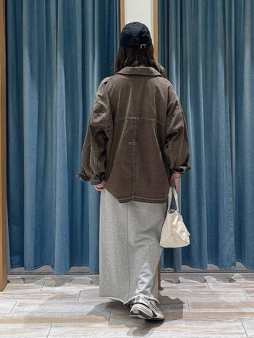 グレー系のTシャツ/カットソー、グレー系のスカート、ブラウン系のデニムジャケットを着用したレディースの春コーディネートの3枚目の写真