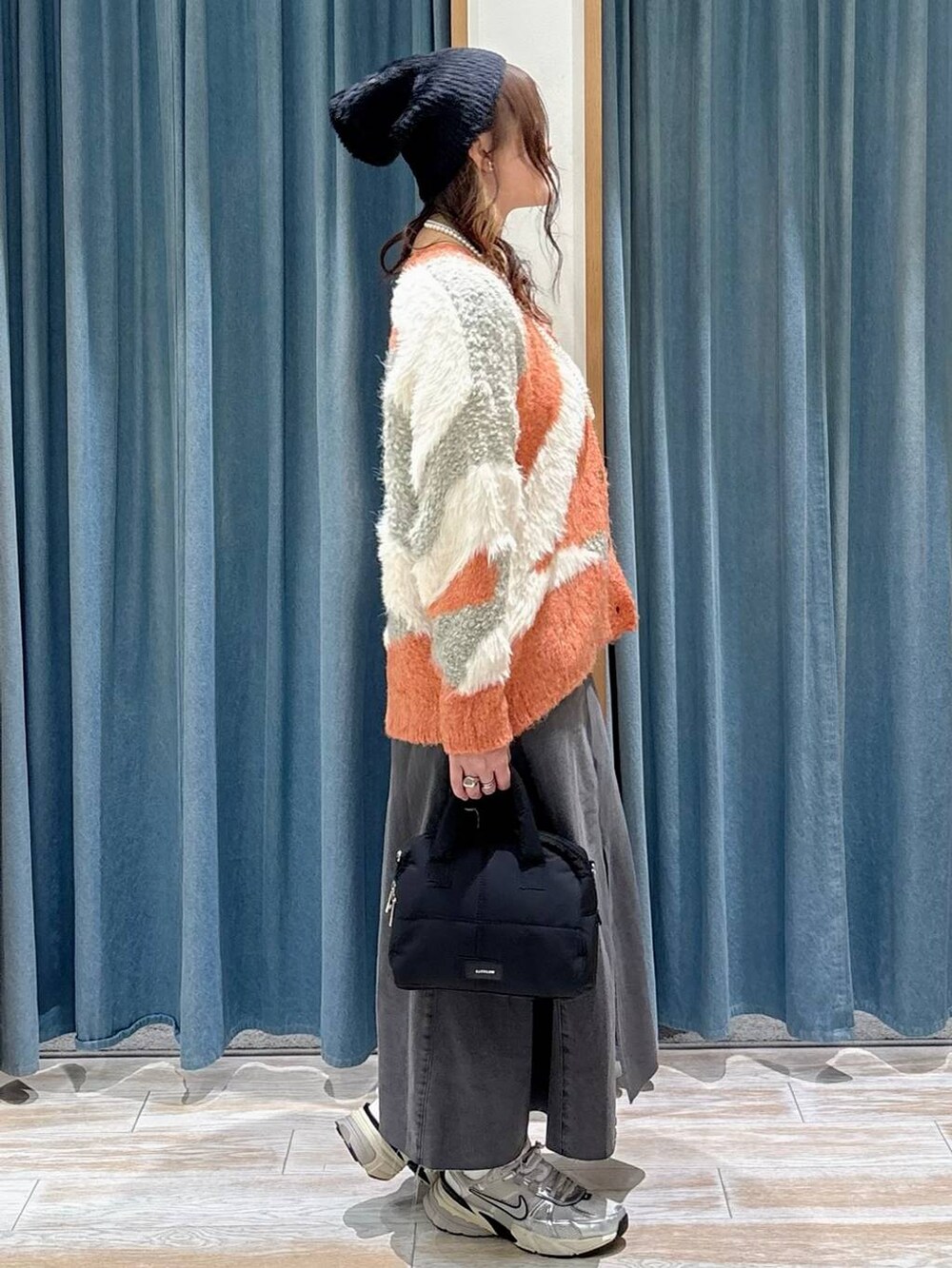 オレンジ系のカーディガン/ボレロ、ブラック系のスカート、ブラック系のボストンバッグを着用したレディースの秋コーディネートの2枚目の写真