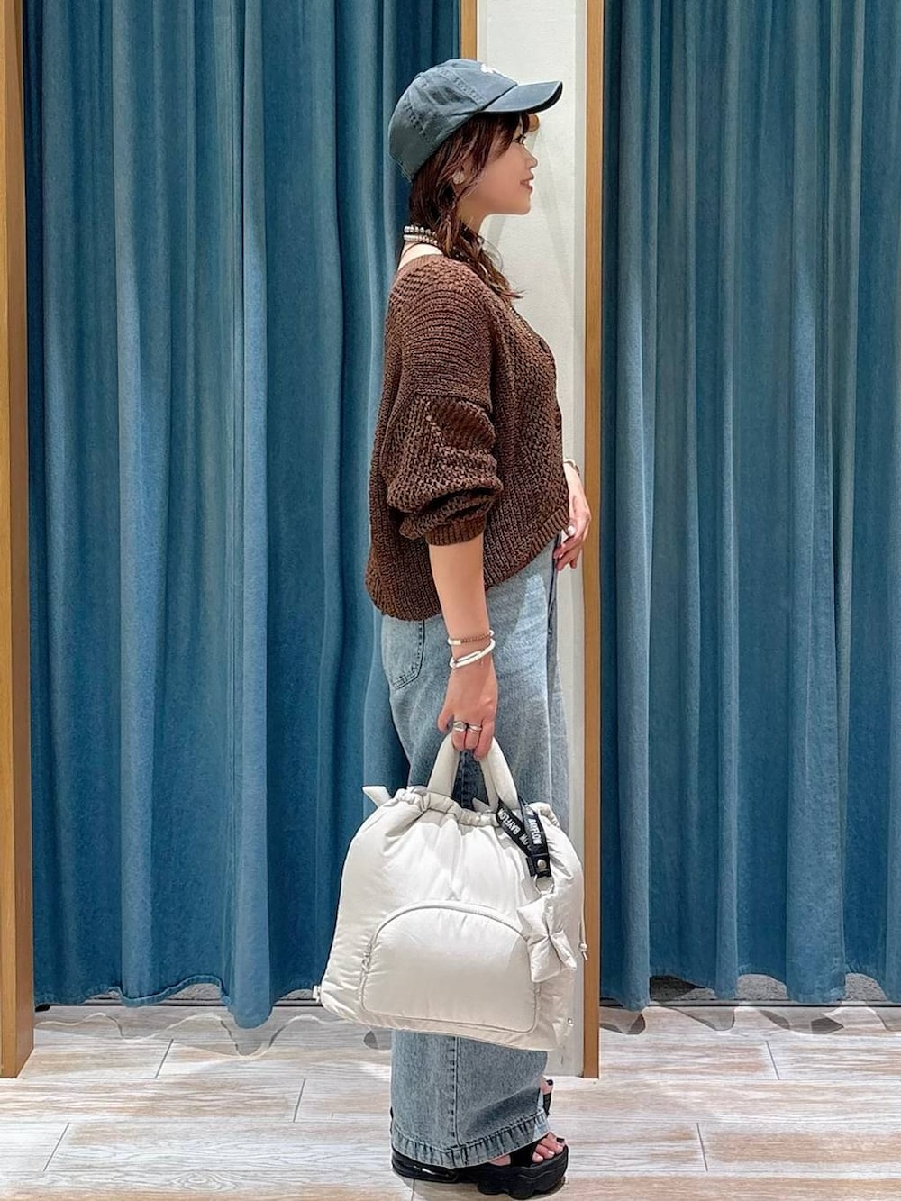 ブラック系のキャミソール、ブルー系のデニムパンツ、ホワイト系のトートバッグを着用したレディースの夏コーディネートの2枚目の写真