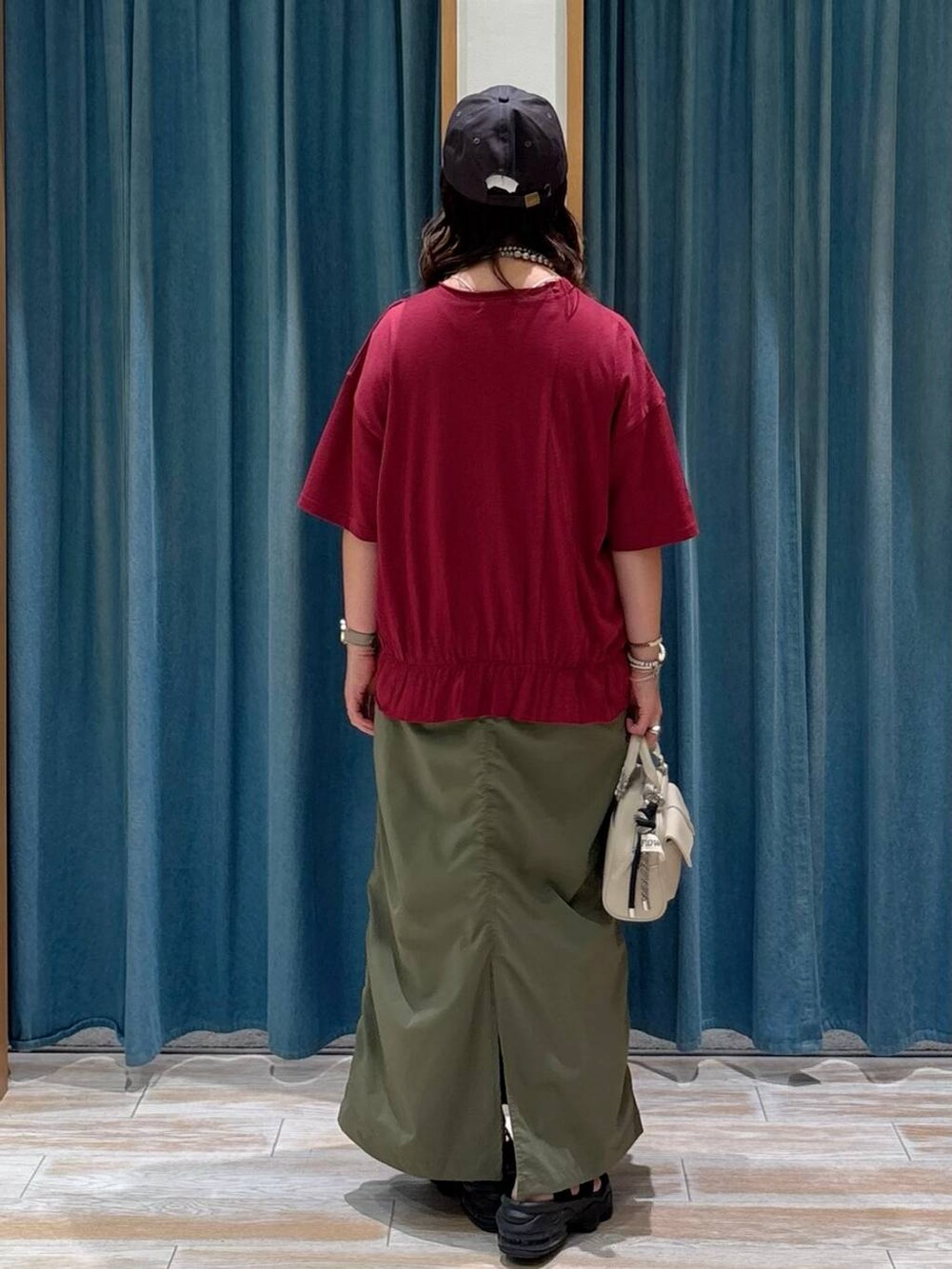 グリーン系のスカート、ホワイト系のボストンバッグ、シルバー系のネックレスを着用したレディースの夏コーディネートの3枚目の写真