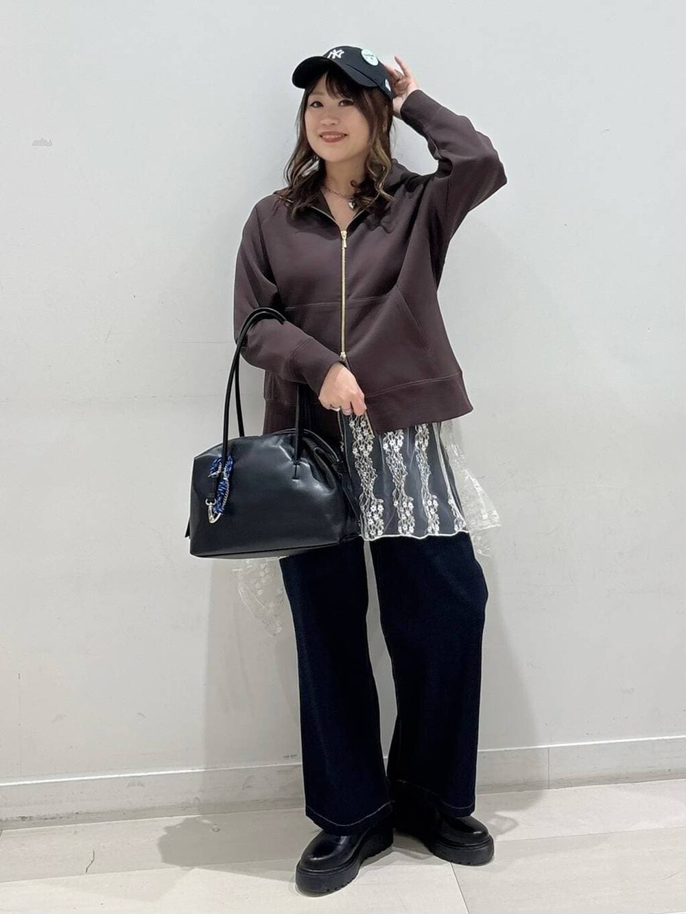 ブラック系のボストンバッグ、ブルー系のデニムパンツ、ブラック系のブーツを着用したレディースの冬コーディネートの4枚目の写真