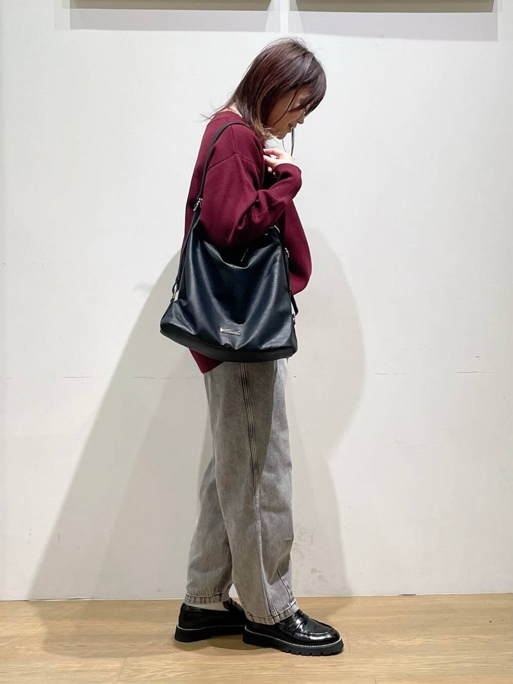 ブラック系のローファー、レッド系のニット/セーター、ブラック系のデニムパンツを着用したレディースの秋コーディネートの2枚目の写真