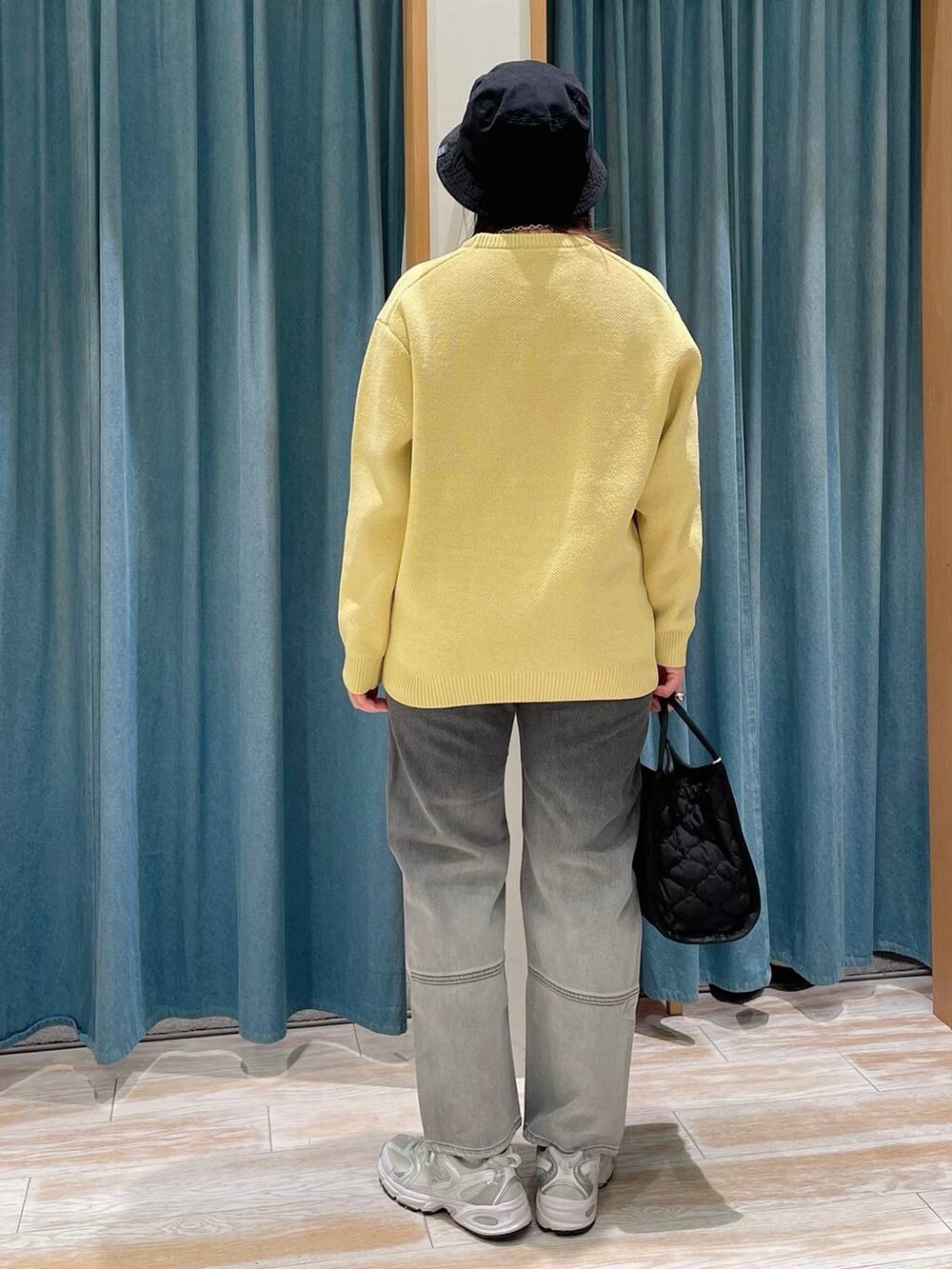 ブラック系のデニムパンツ、ブラック系のハンドバッグ、イエロー系のニット/セーターを着用したレディースの冬コーディネートの2枚目の写真