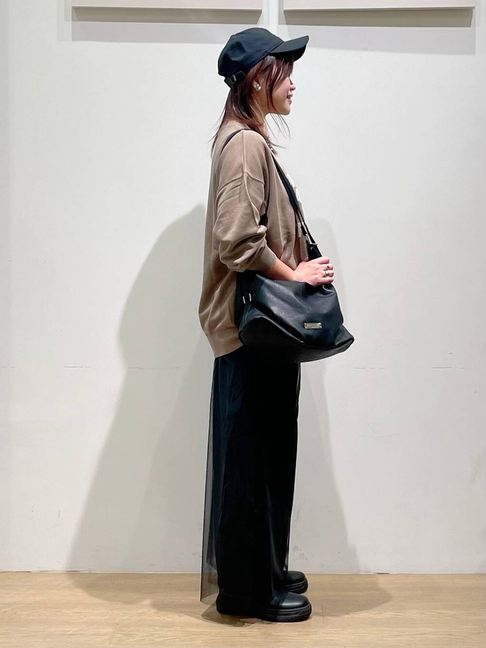 ブラウン系のスウェット、ブラック系のブーツ、ブラック系のその他パンツを着用したレディースの秋コーディネートの2枚目の写真