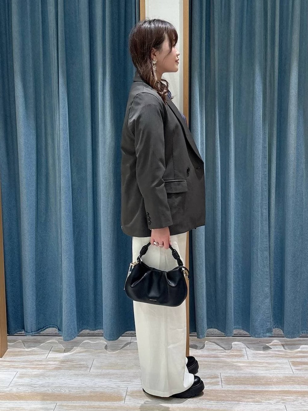 ブラック系のブーツ、ブラック系のハンドバッグ、グレー系のテーラードジャケットを着用したレディースの春コーディネートの2枚目の写真