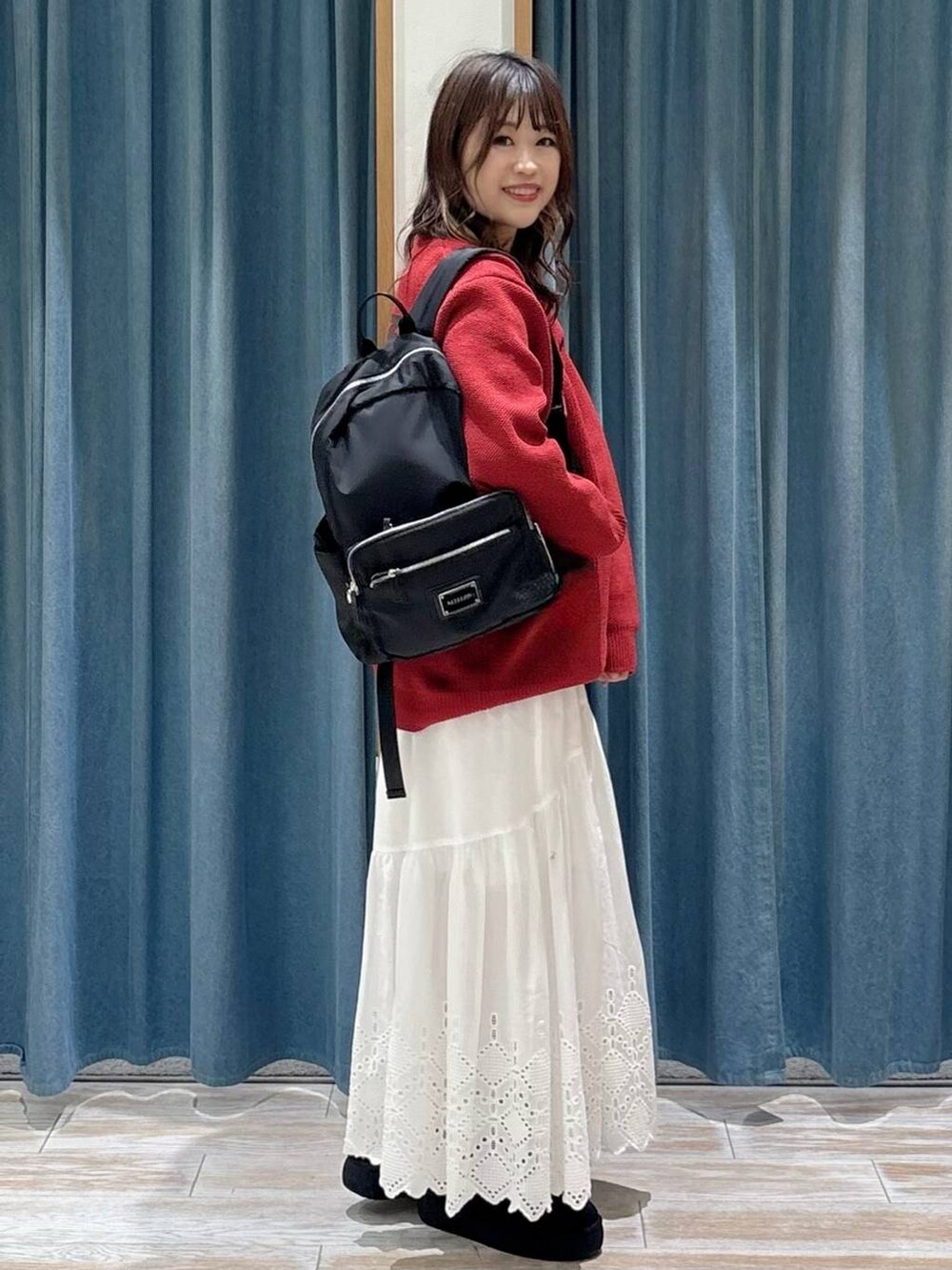 ブラック系のブーツ、ブラック系のバックパック/リュック、ホワイト系のスカートを着用したレディースの秋コーディネートの2枚目の写真