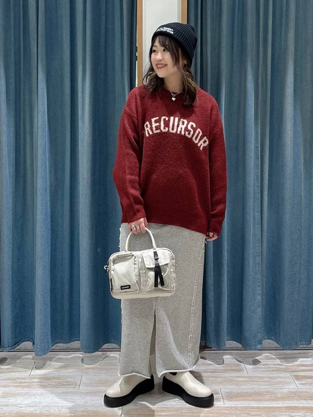 ベージュ系のハンドバッグ、ベージュ系のブーツ、レッド系のニット/セーターを着用したレディースの冬コーディネートの2枚目の写真