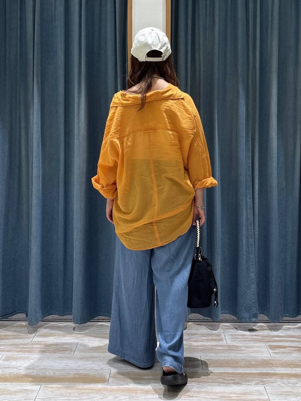 オレンジ系のシャツ/ブラウス、ブルー系のデニムパンツ、ブラック系のショルダーバッグを着用したレディースの夏コーディネートの3枚目の写真
