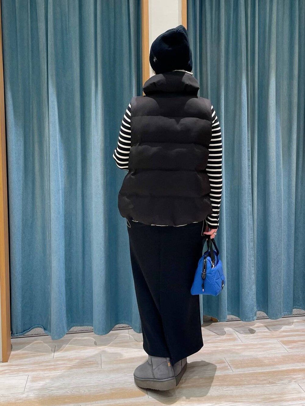 ブラック系のニット/セーター、ブラック系のベスト、グレー系のブーツを着用したレディースの冬コーディネートの3枚目の写真