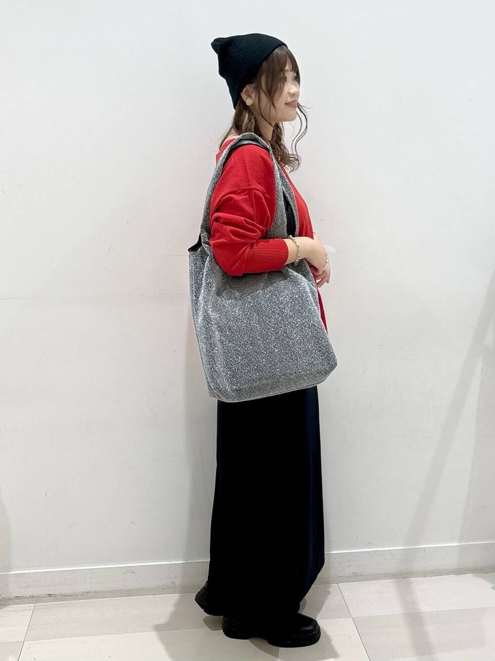 ブラック系のスカート、レッド系のニット/セーター、ブラック系のブーツを着用したレディースの秋コーディネートの2枚目の写真