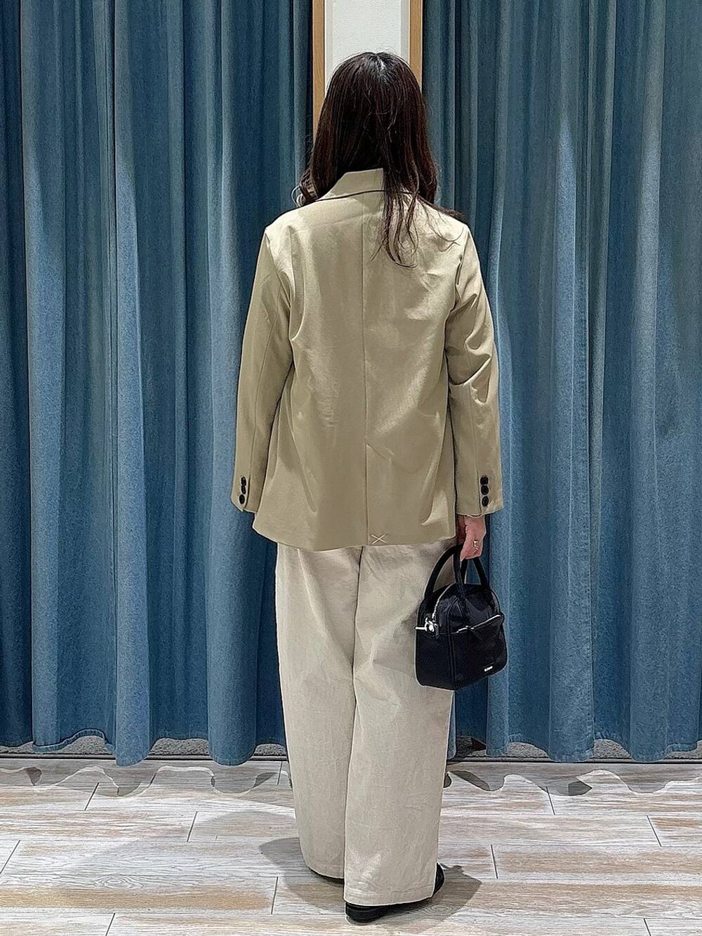 ブラック系のハンドバッグ、ブラック系のローファー、ベージュ系のテーラードジャケットを着用したレディースの冬コーディネートの3枚目の写真