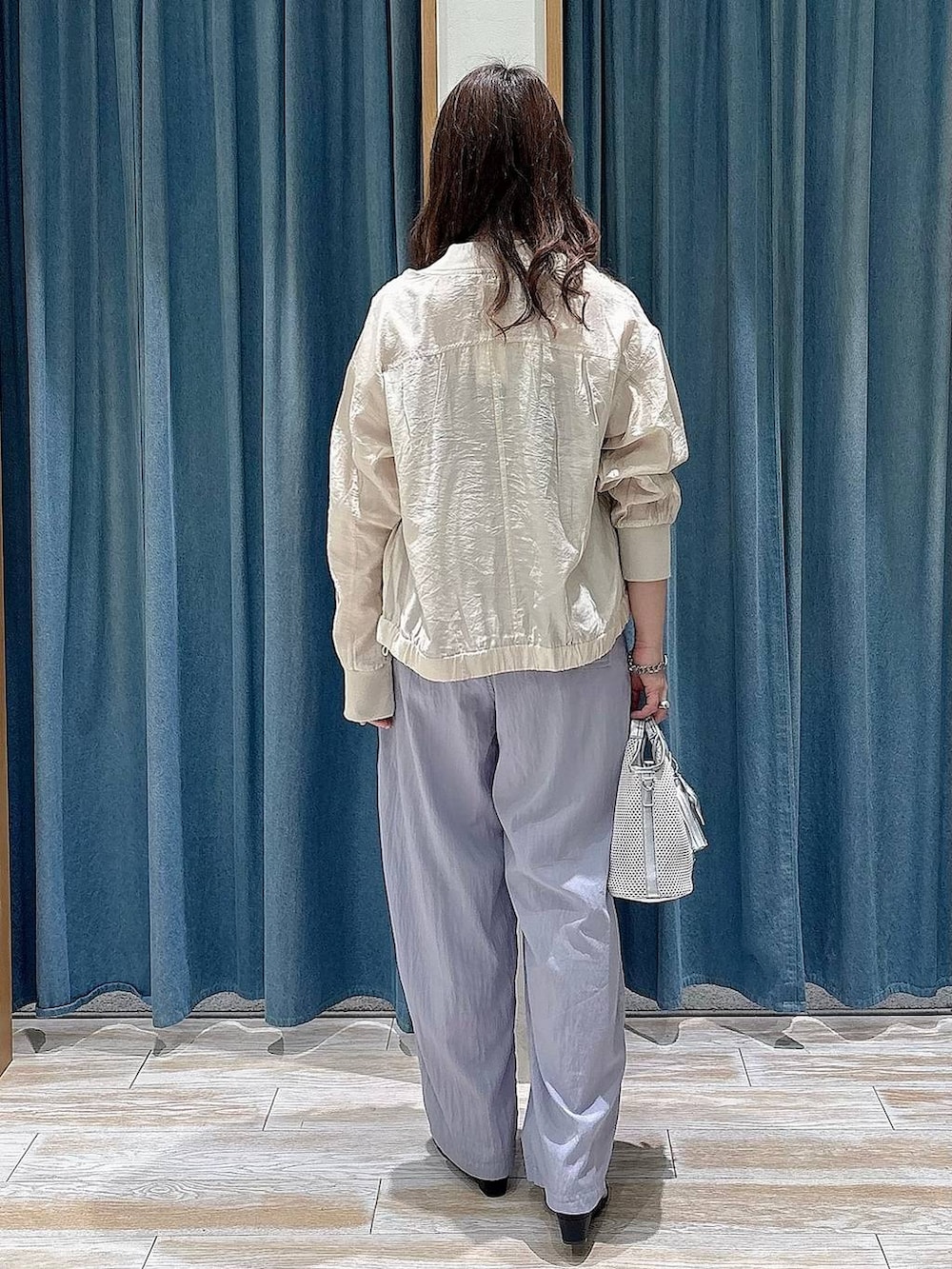 グレー系のショルダーバッグ、ホワイト系のブルゾン、パープル系のその他パンツを着用したレディースの春コーディネートの3枚目の写真