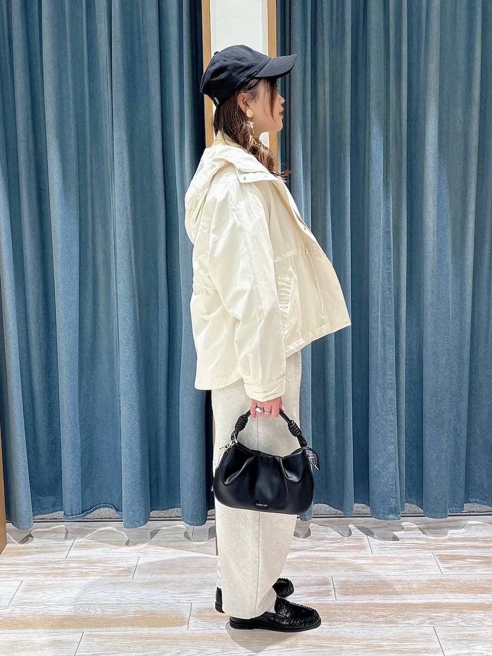 イエロー系のシャツ/ブラウス、ホワイト系のマウンテンパーカー、ブラック系のハンドバッグを着用したレディースの春コーディネートの2枚目の写真