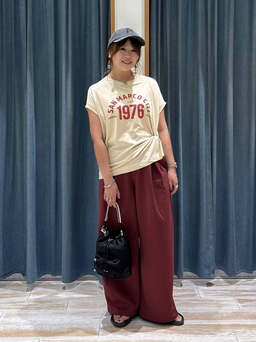 ベージュ系のTシャツ/カットソー、レッド系のスウェットパンツ、ブラック系のショルダーバッグを着用したレディースの夏コーディネートの2枚目の写真