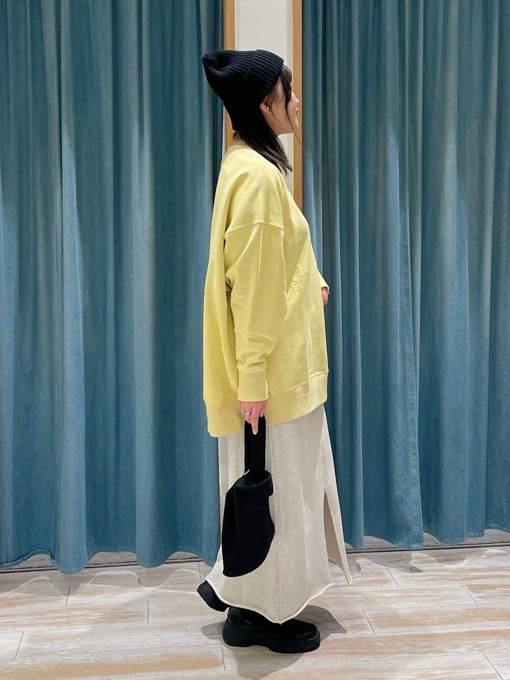 ブラック系のブーツ、イエロー系のスウェット、ベージュ系のスカートを着用したレディースの冬コーディネートの2枚目の写真