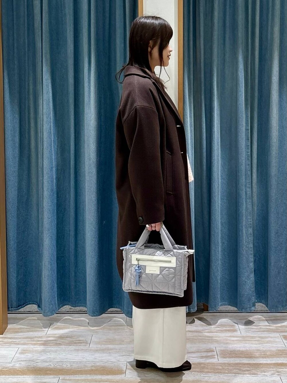 グレー系のショルダーバッグ、ベージュ系のその他パンツ、ブラウン系のチェスターコートを着用したレディースの冬コーディネートの2枚目の写真