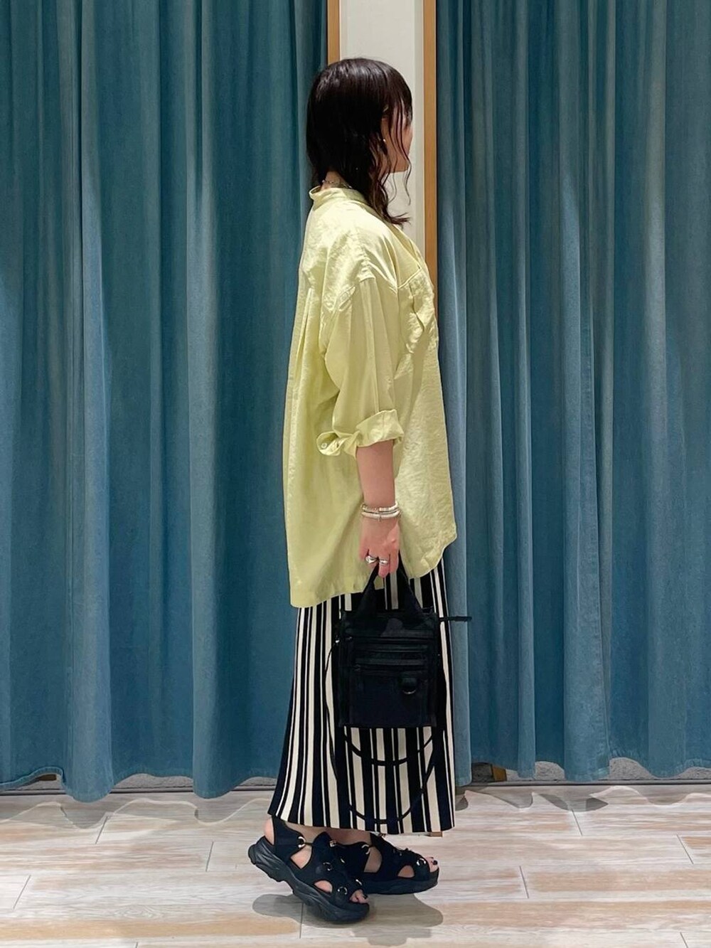 イエロー系のシャツ/ブラウス、ブラック系のショルダーバッグ、ブラック系のサンダルを着用したレディースの春コーディネートの2枚目の写真