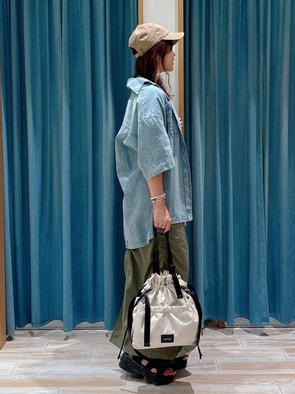 ホワイト系のトートバッグ、グリーン系のスカート、ブルー系のシャツ/ブラウスを着用したレディースの夏コーディネートの2枚目の写真