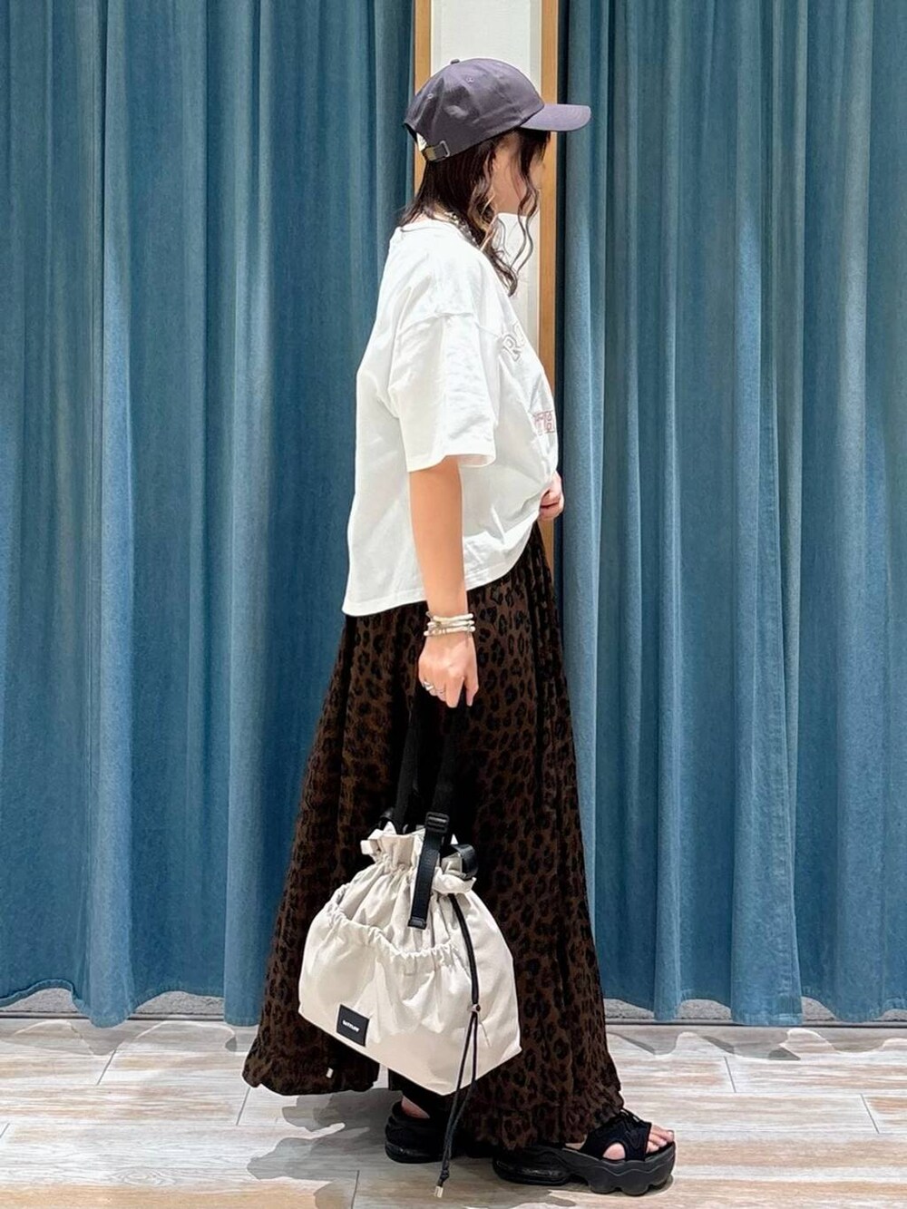 ホワイト系のトートバッグ、ブラウン系のスカート、ホワイト系のTシャツ/カットソーを着用したレディースの夏コーディネートの2枚目の写真