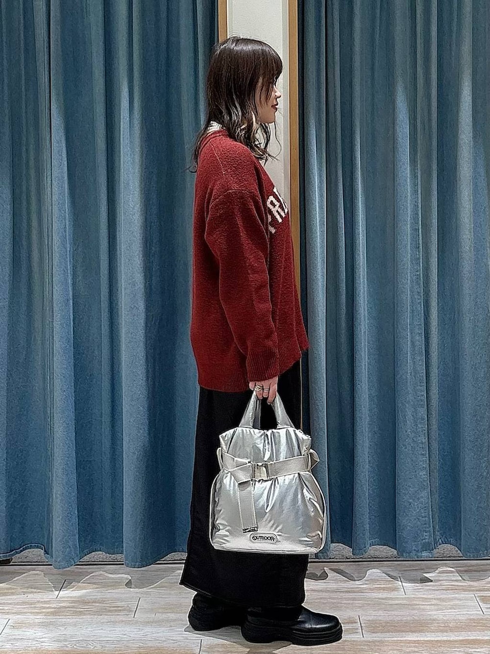 シルバー系のトートバッグ、ブラック系のブーツ、レッド系のニット/セーターを着用したレディースの冬コーディネートの2枚目の写真