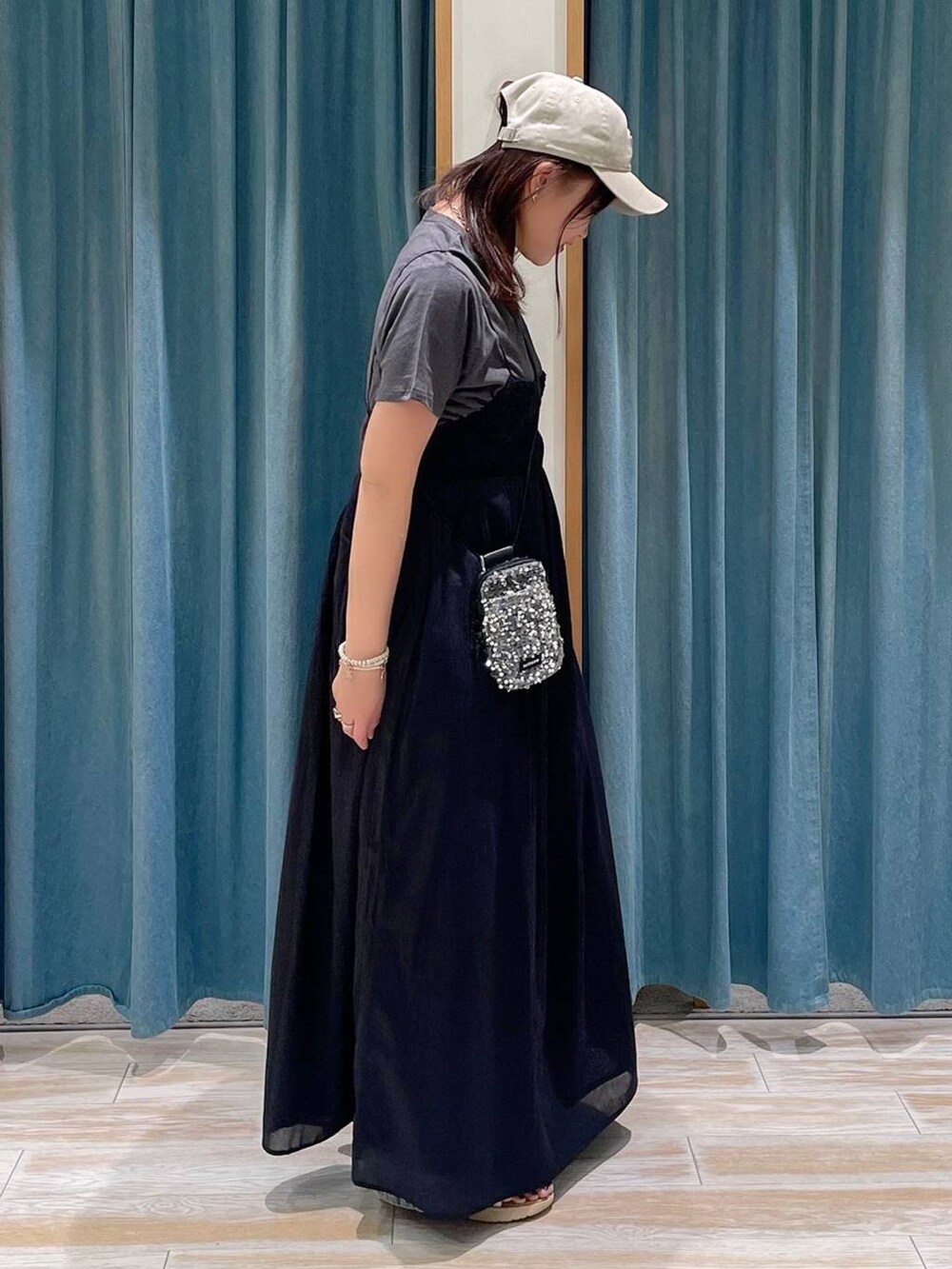 グレー系のショルダーバッグ、ブルー系のデニムパンツ、ブラック系のワンピースを着用したレディースの春コーディネートの2枚目の写真